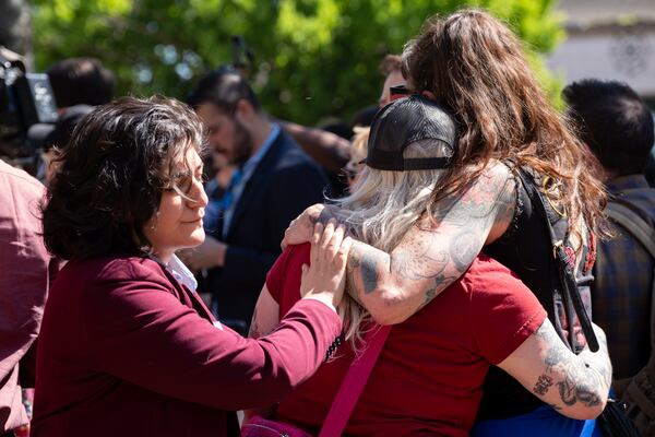 Atlanta City Councilperson Liliana Bakhtiari, left, comforts friends of Cooper Schoenke, who was killed when the car he was driving was hit by a suspect fleeing the Georgia State Patrol earlier this week in Little Five Points.   Ben Gray for the Atlanta Journal-Constitution